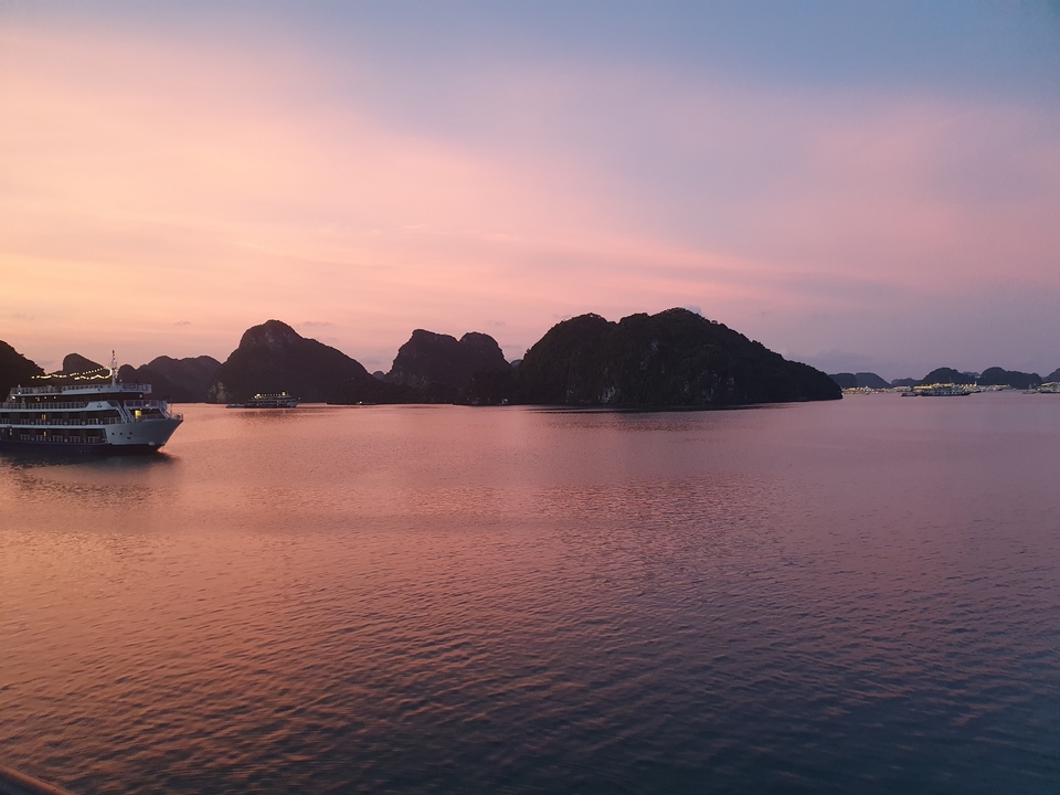 Bateaux de croisière ancrés au coucher du soleil dans une baie pittoresque.