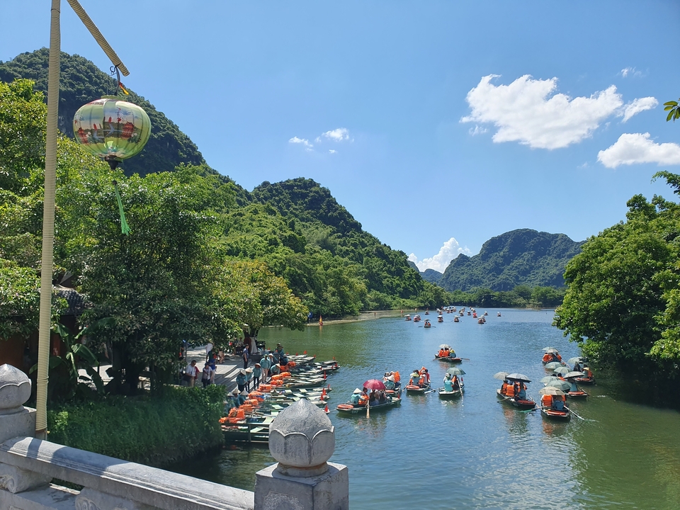 Bateaux colorés sur une rivière avec des montagnes vertes.