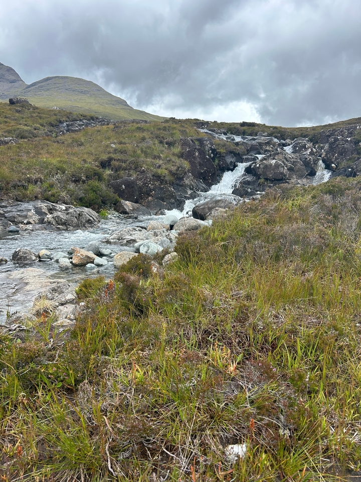 Small waterfall flowing over rocks in a green area.