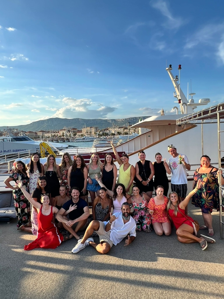 Group of people on a boat with mountains and city view.