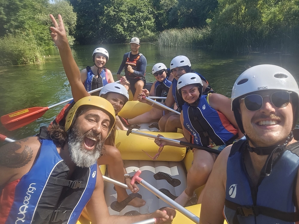 Group of people rafting on a river in a forested area.