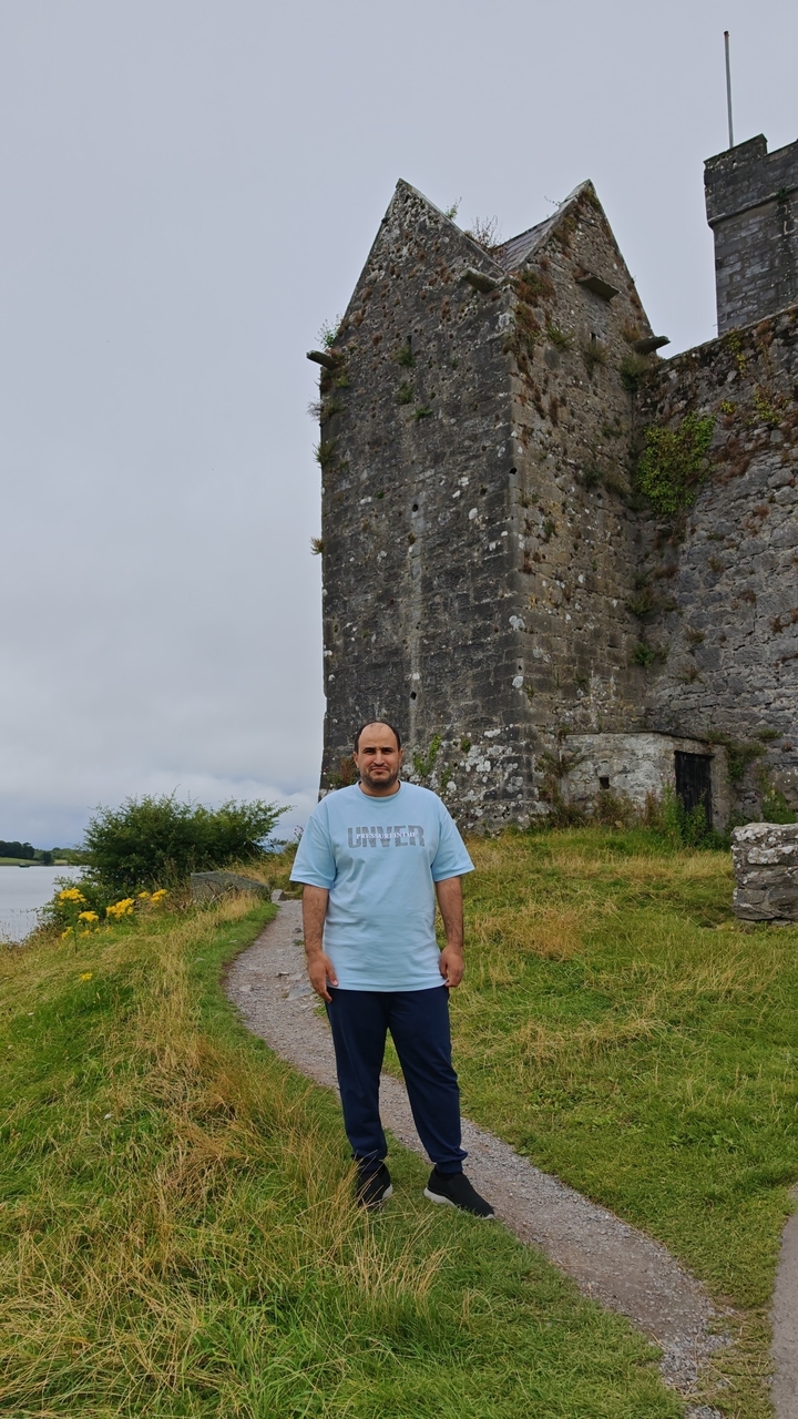 A person standing in front of a historic tower near water.