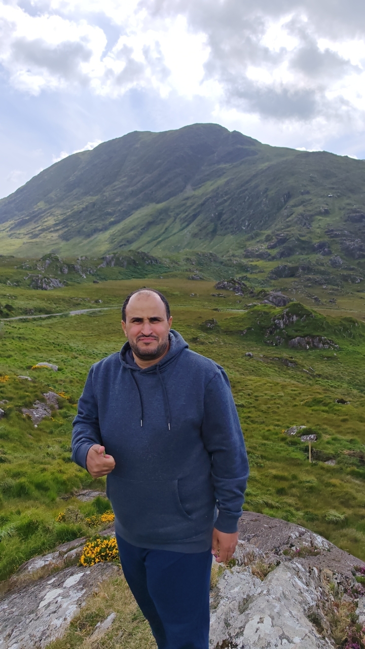 A person in a hooded sweatshirt in a mountainous area.