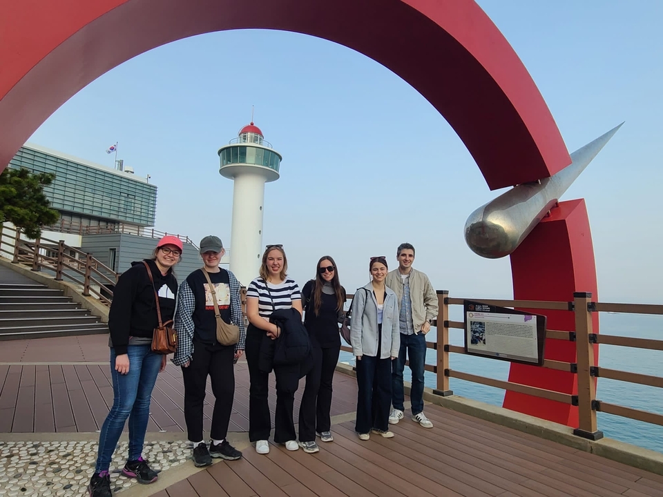 Groupe de personnes posant près d'un phare et d'une sculpture rouge sur une promenade.