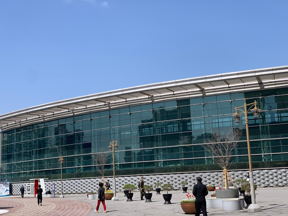 Bâtiment moderne en verre et acier avec un toit courbé.