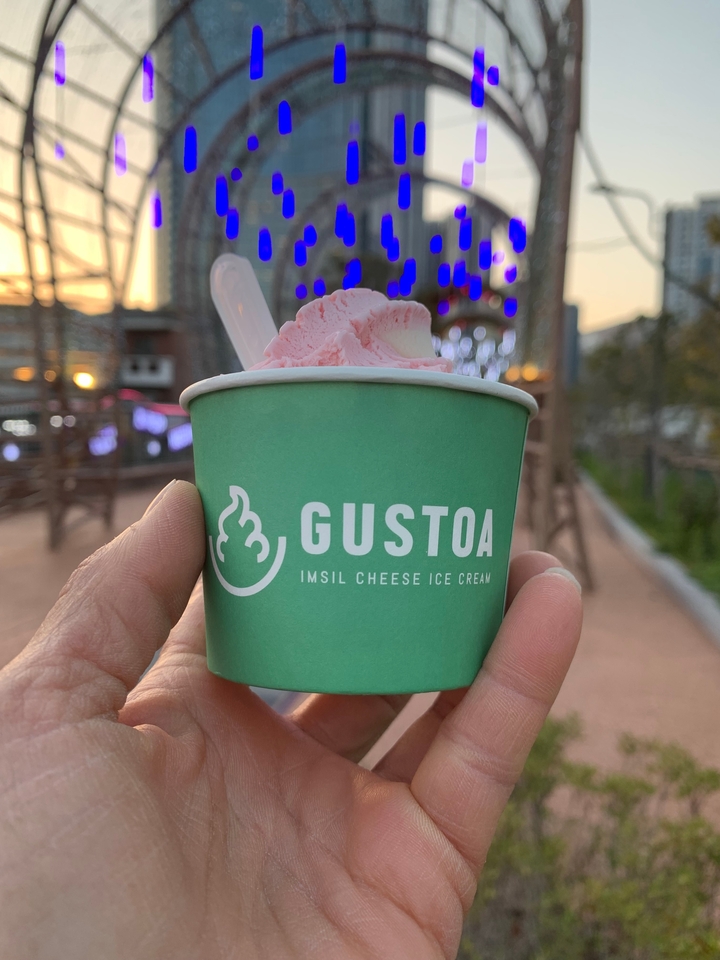 Coupe de glace rose de GUSTOA tenue dans la main.