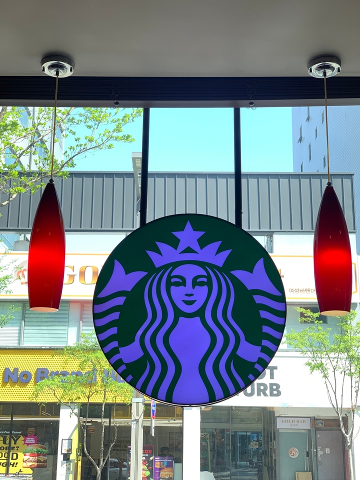 Enseigne Starbucks avec des lumières rouges et un bâtiment en arrière-plan.