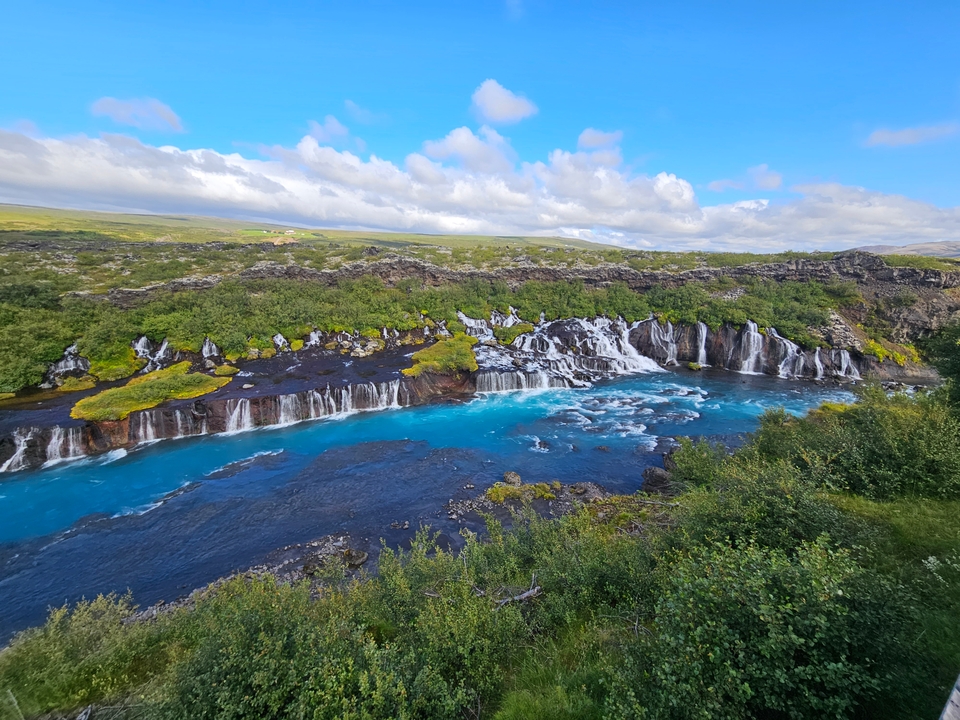 Waterfall with turquoise water and green surroundings.