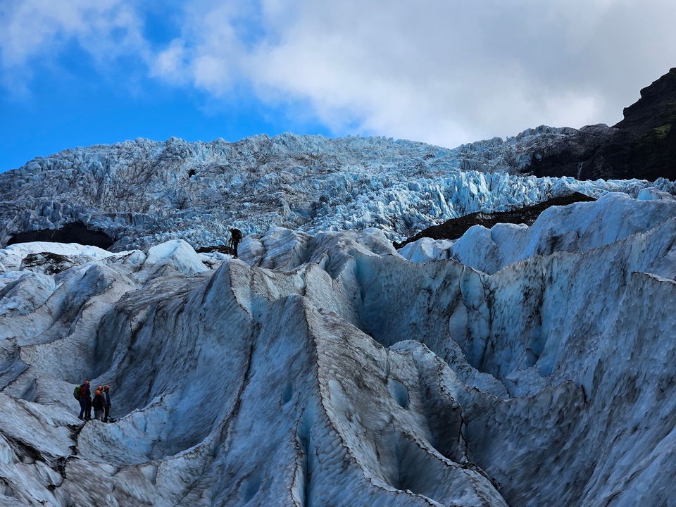 People walking on a glacier with blue ice.