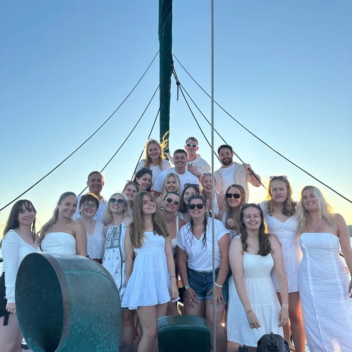 Group of people on a boat, dressed in white.