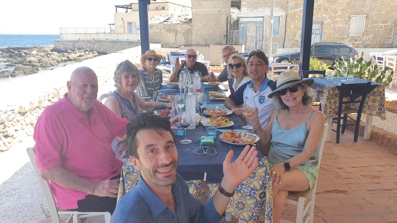 Group of people enjoying a meal at a seaside table.