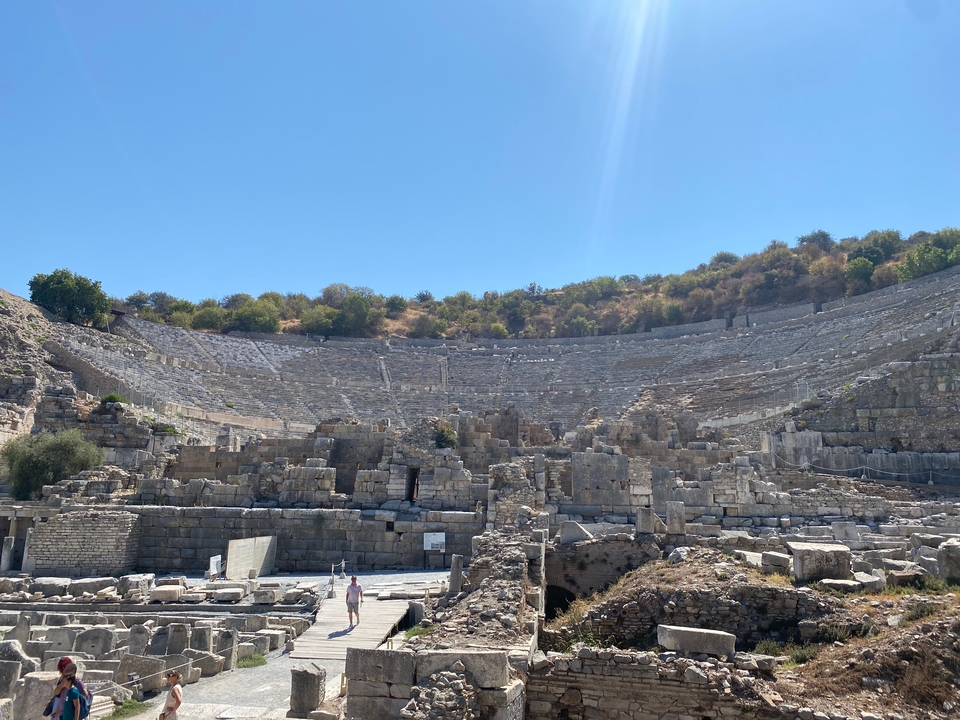 Amphithéâtre antique avec des gradins en pierre et des visiteurs qui explorent.