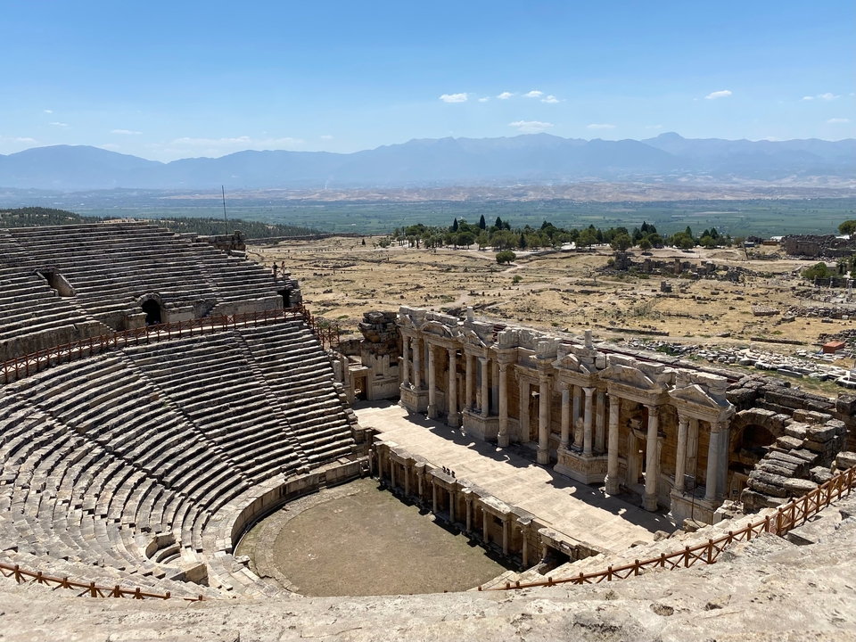 Ruines d'un grand théâtre antique avec une scène détaillée.