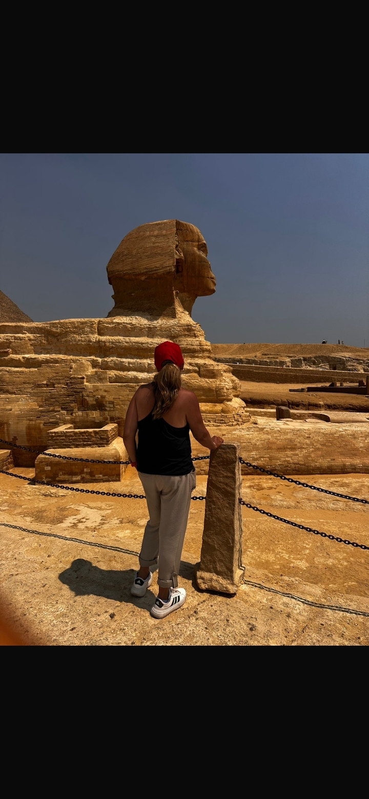 Une personne regardant le Sphinx dans un cadre archéologique.