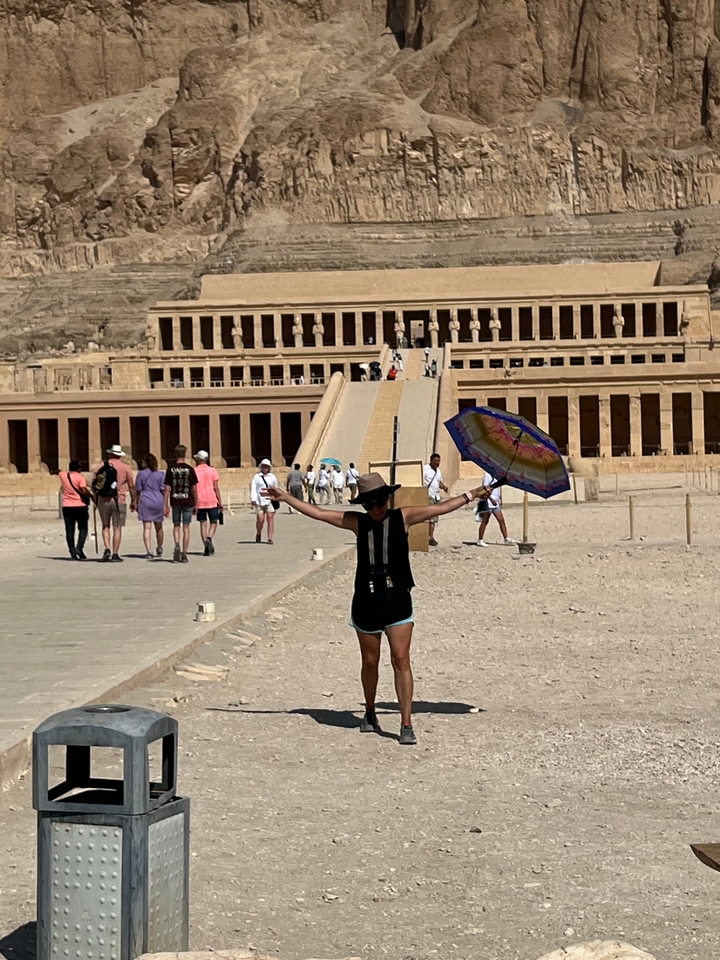 Une personne qui pose avec un monument historique en arrière-plan.