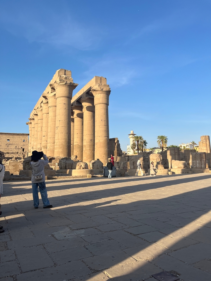 Des touristes explorant des ruines historiques avec de grandes colonnes de pierre.