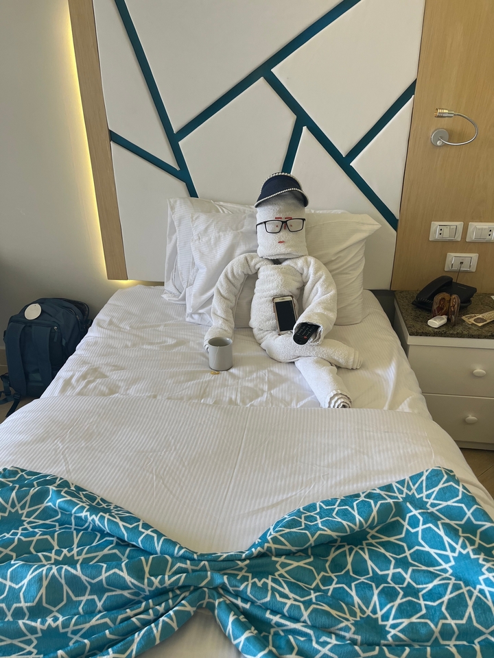 Art de serviette en forme de personne avec des lunettes de soleil sur un lit.