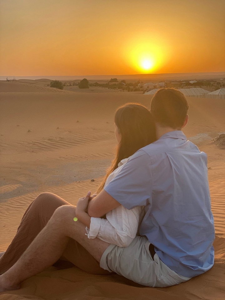 Couple assis dans les dunes de sable au coucher du soleil.