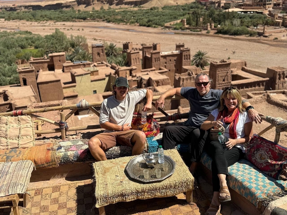 Groupe de personnes assises sur un tapis avec vue sur une kasbah.
