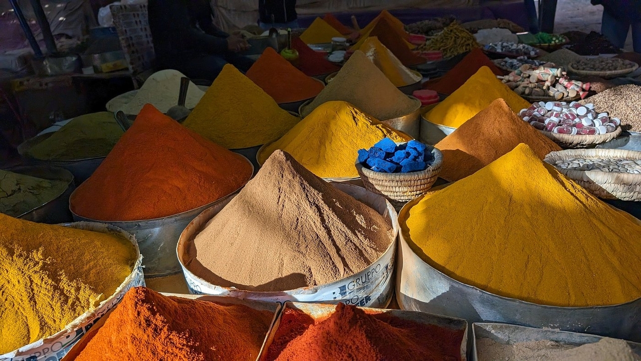 Des épices et herbes colorées exposées dans un marché.