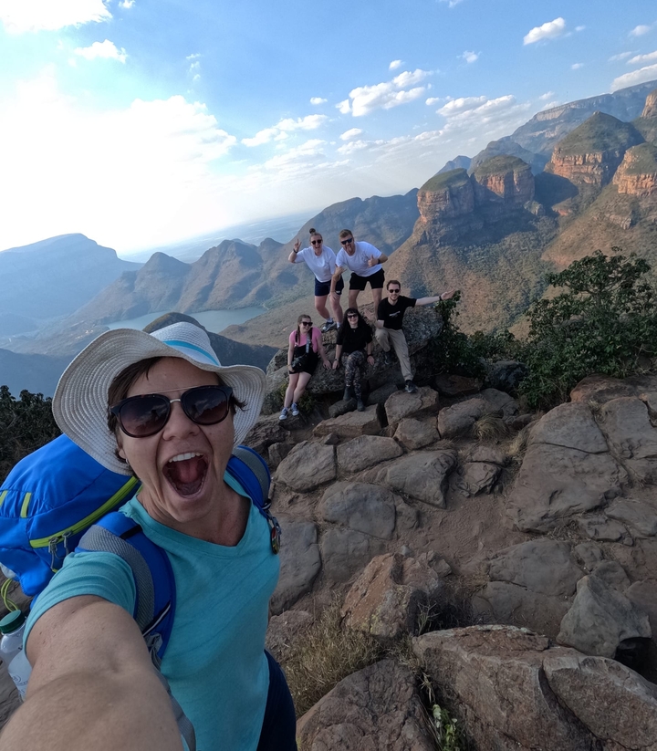 Hikers posing on a rocky cliff with a breathtaking canyon view.