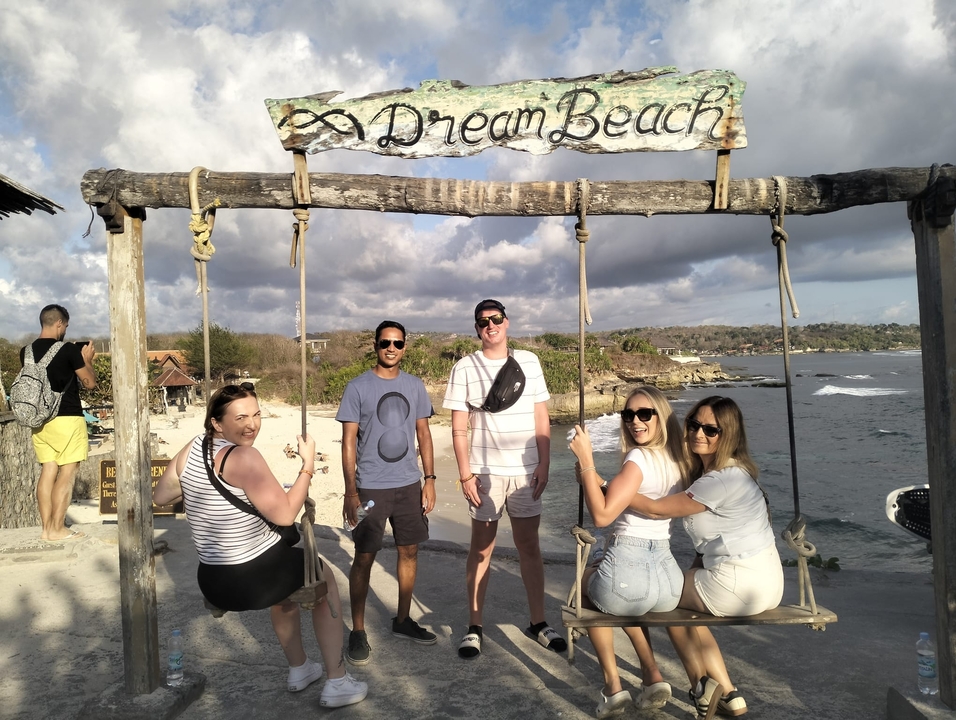 Friends sitting on a swing set at the beach.