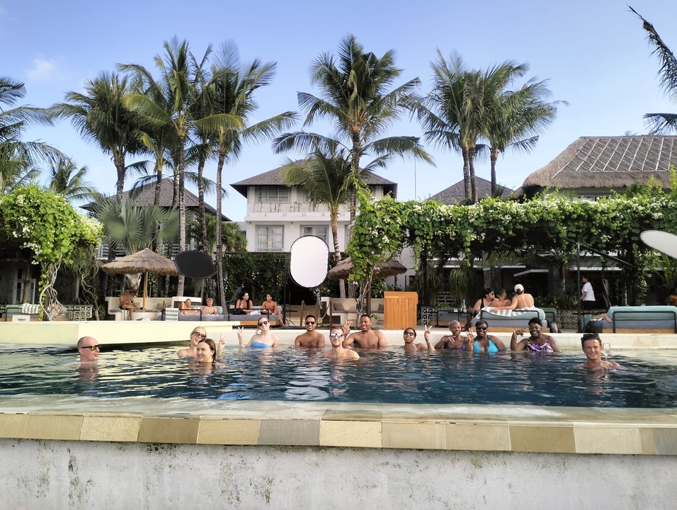 Group of people relaxing in a swimming pool with tropical surroundings.