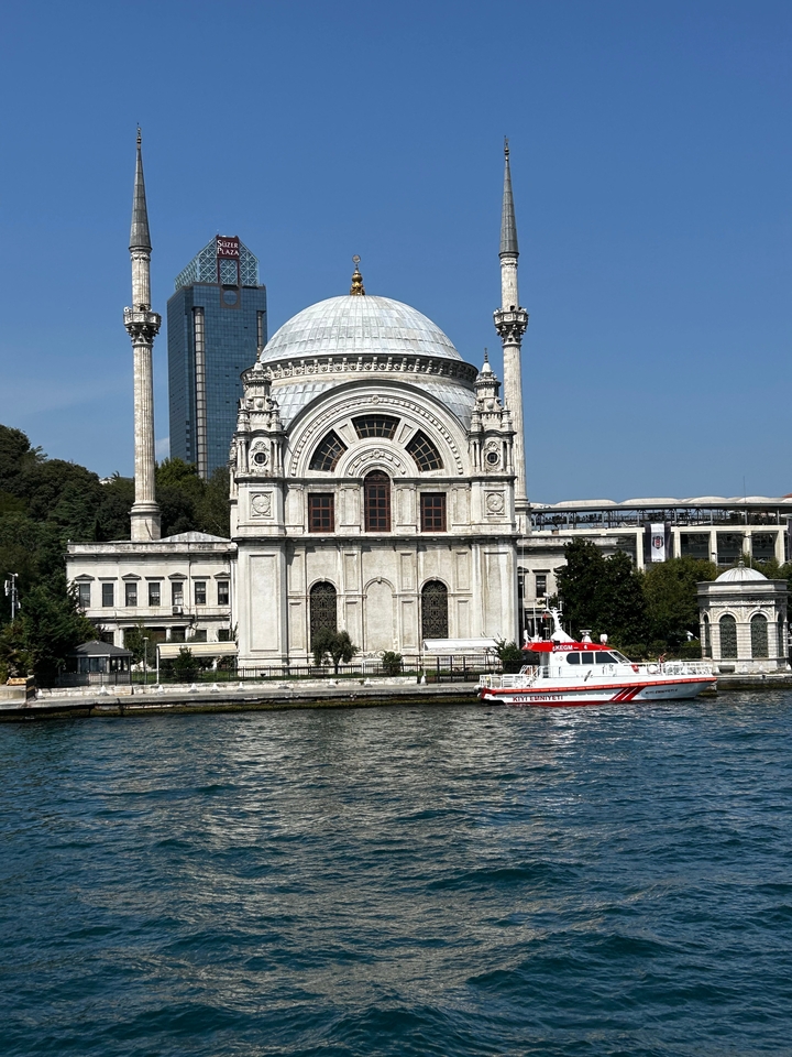 Bâtiment historique au bord d'une rivière avec un petit bateau amarré à proximité.