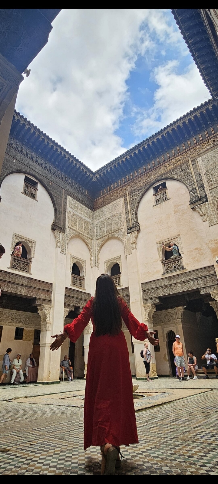 Des gens dans une cour d'architecture marocaine.