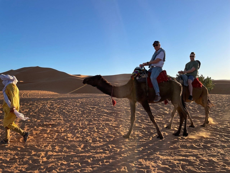 Des touristes faisant du chameau dans le paysage désertique.