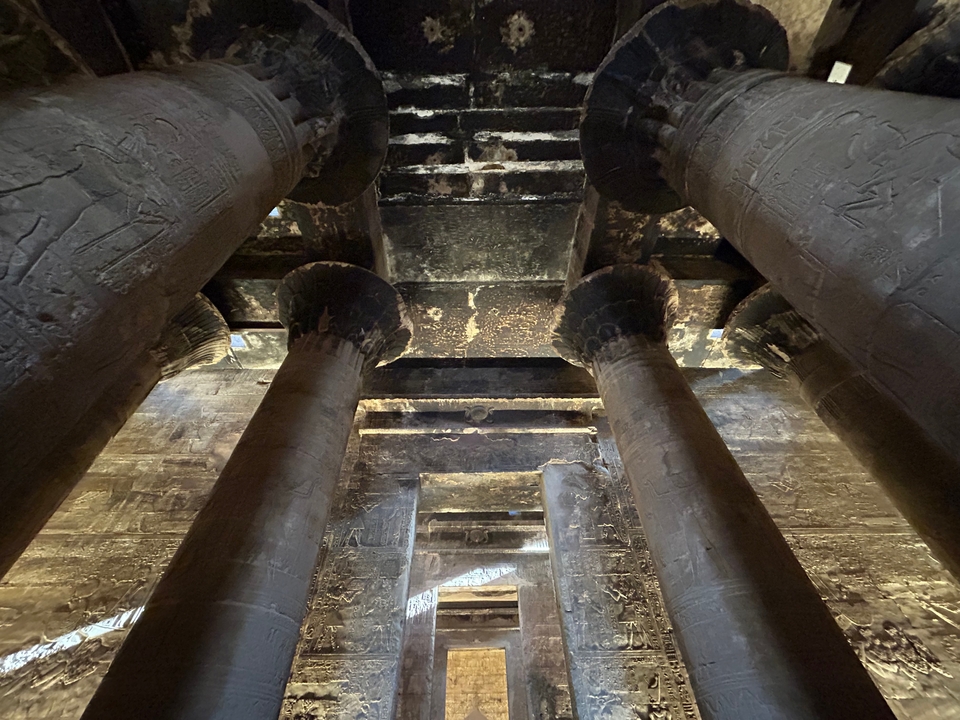 Interior of an ancient Egyptian temple showing columns with carvings.