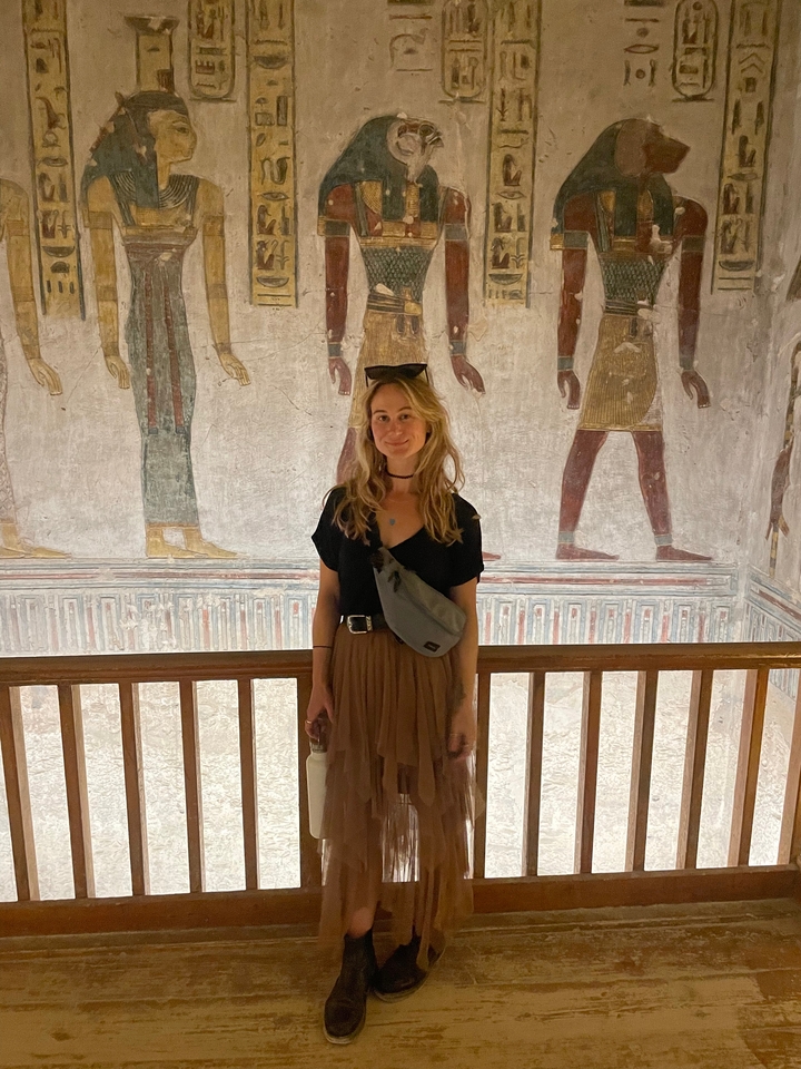 Person posing in front of wall carvings.