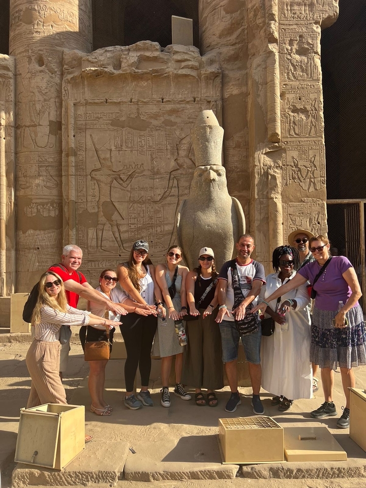 A group of tourists posing in front of an ancient Egyptian temple.