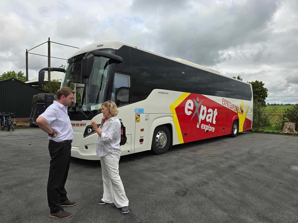 Autocar avec la marque 'expat explore' et des personnes à proximité.