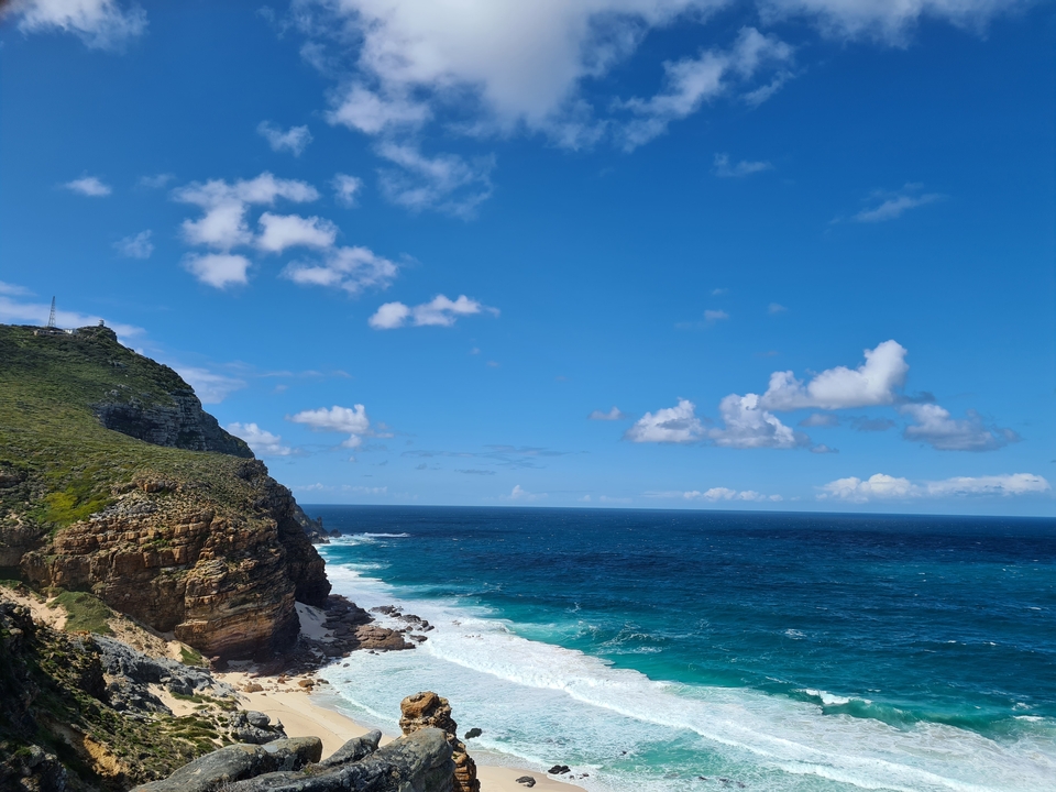Coastline with cliffs and ocean waves under a blue sky.