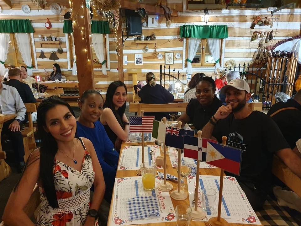 Groupe de personnes assises à une table de restaurant avec des drapeaux affichés.