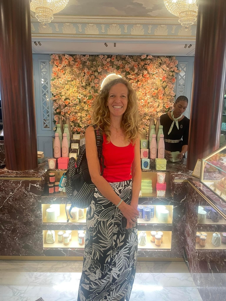 Personne souriante devant un étalage de marchandises colorées dans un magasin.