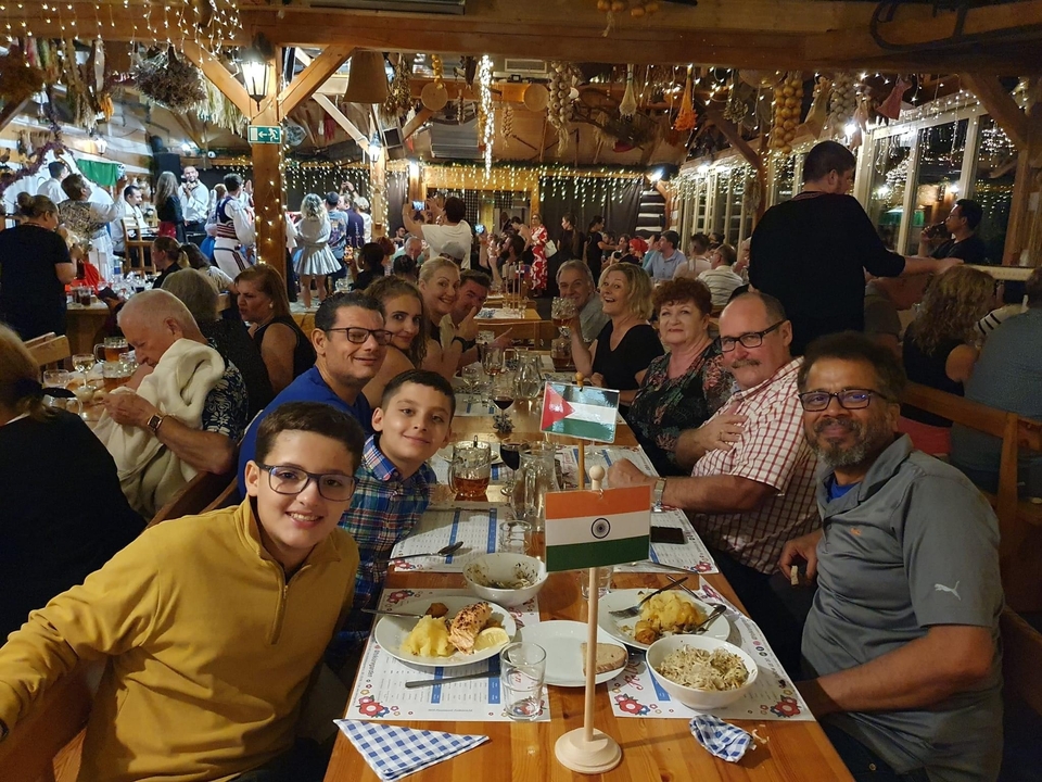 Grand groupe profitant d'un repas ensemble avec divers drapeaux nationaux sur la table.