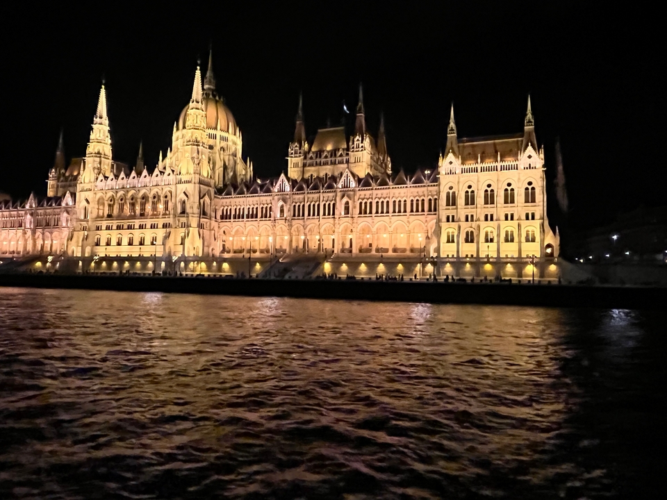 Bâtiment du parlement illuminé se reflétant sur une rivière la nuit.