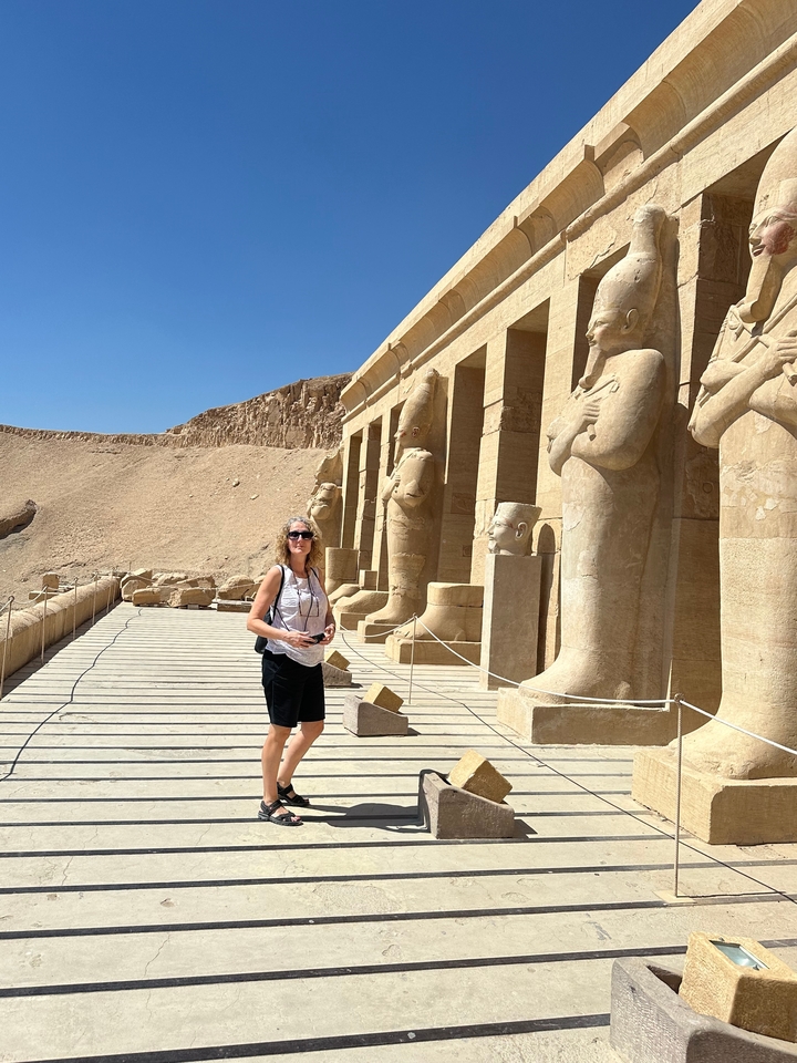 Woman walking in an ancient Egyptian temple with statues.