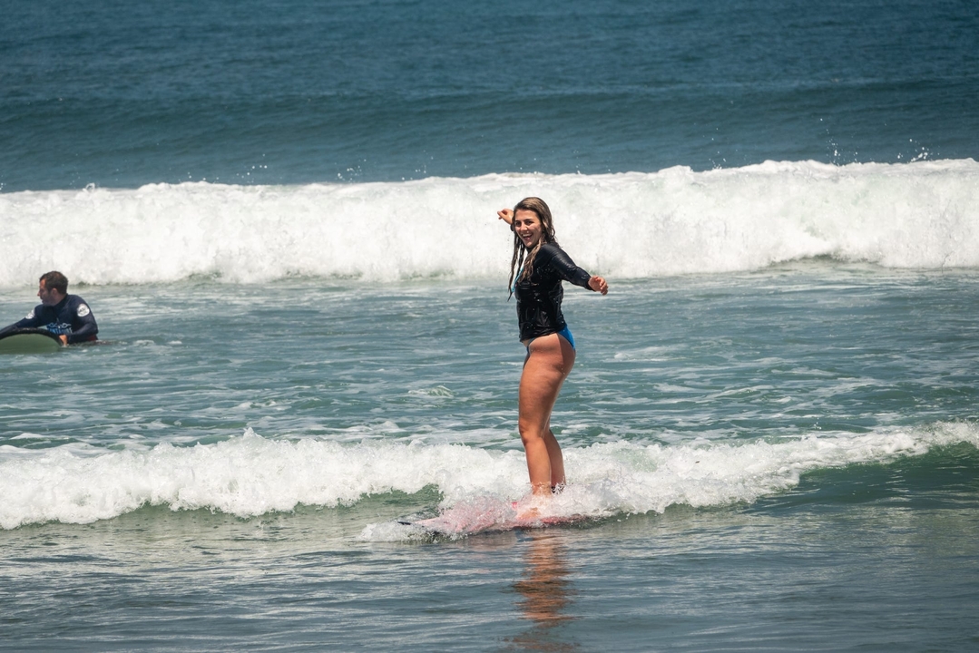 A woman riding a surfboard on a small wave in the ocean.