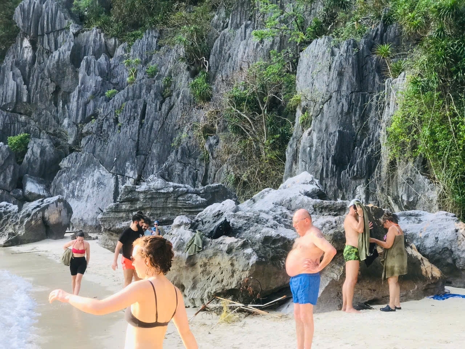 Plage avec formations rocheuses et personnes profitant du soleil.