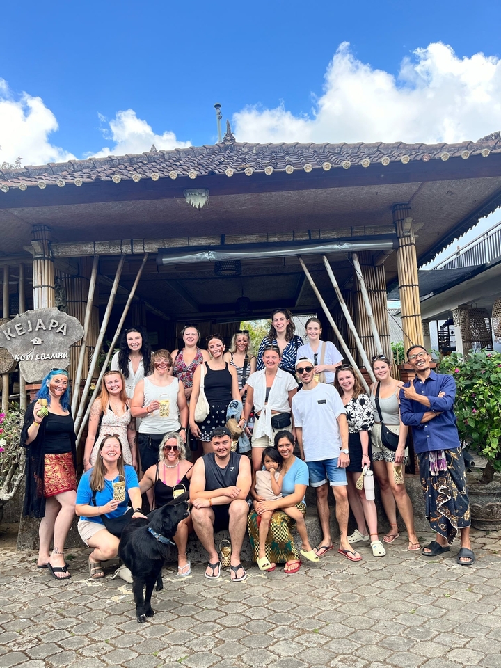 Group of people posing together in front of a bamboo structure.