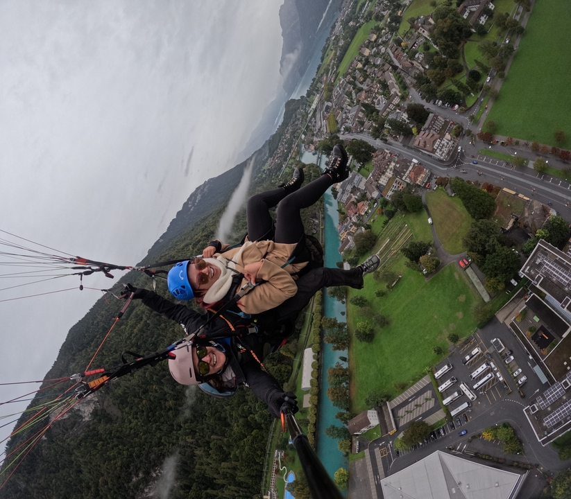 Person paragliding over a city with a view.