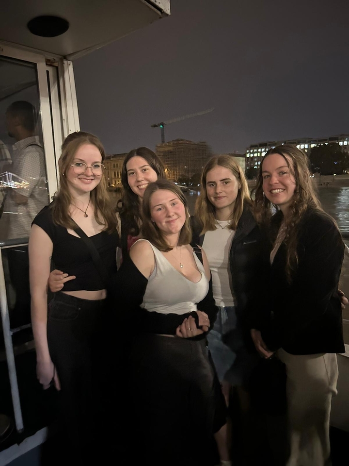 A group of friends posing at night with city lights behind them.