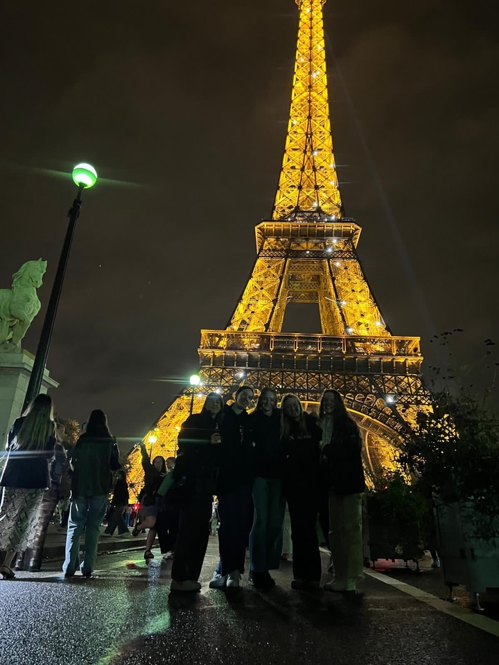 Illuminated Eiffel Tower with people in the foreground.