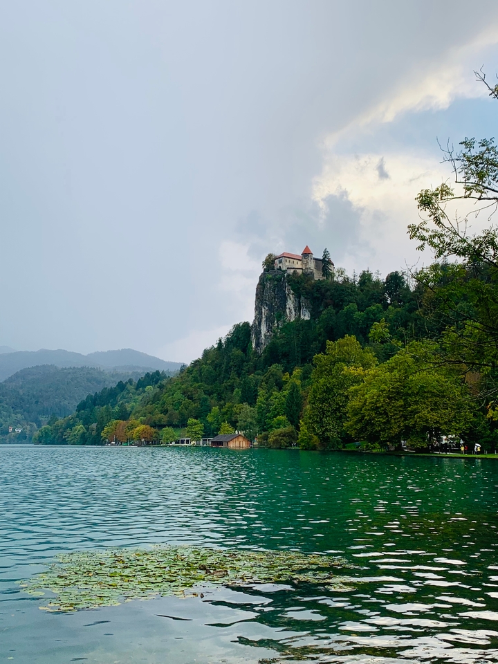 Scenic view of a castle on a rocky hill by the lake.