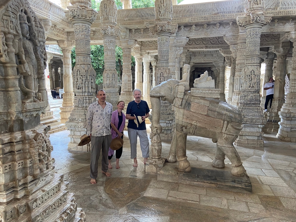 Trois personnes debout dans un temple en pierre avec une statue d'éléphant.
