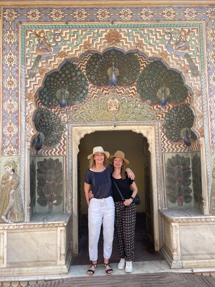 Deux femmes debout devant une entrée ornée d'un paon.