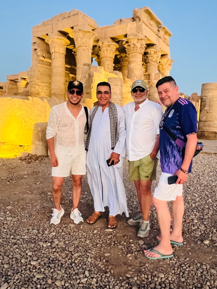 A group of people in front of ancient ruins at dusk.